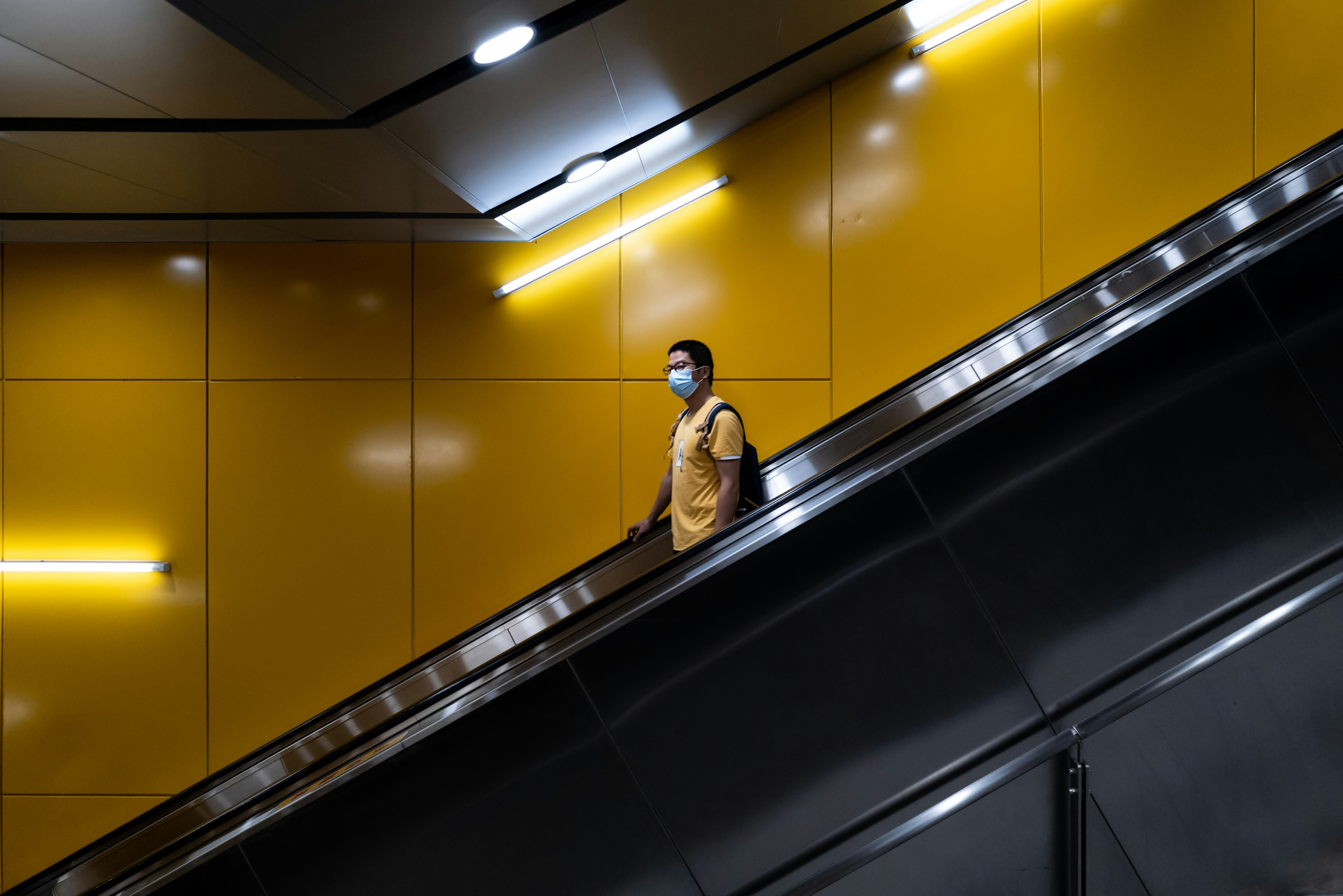 man in brown coat standing on escalator